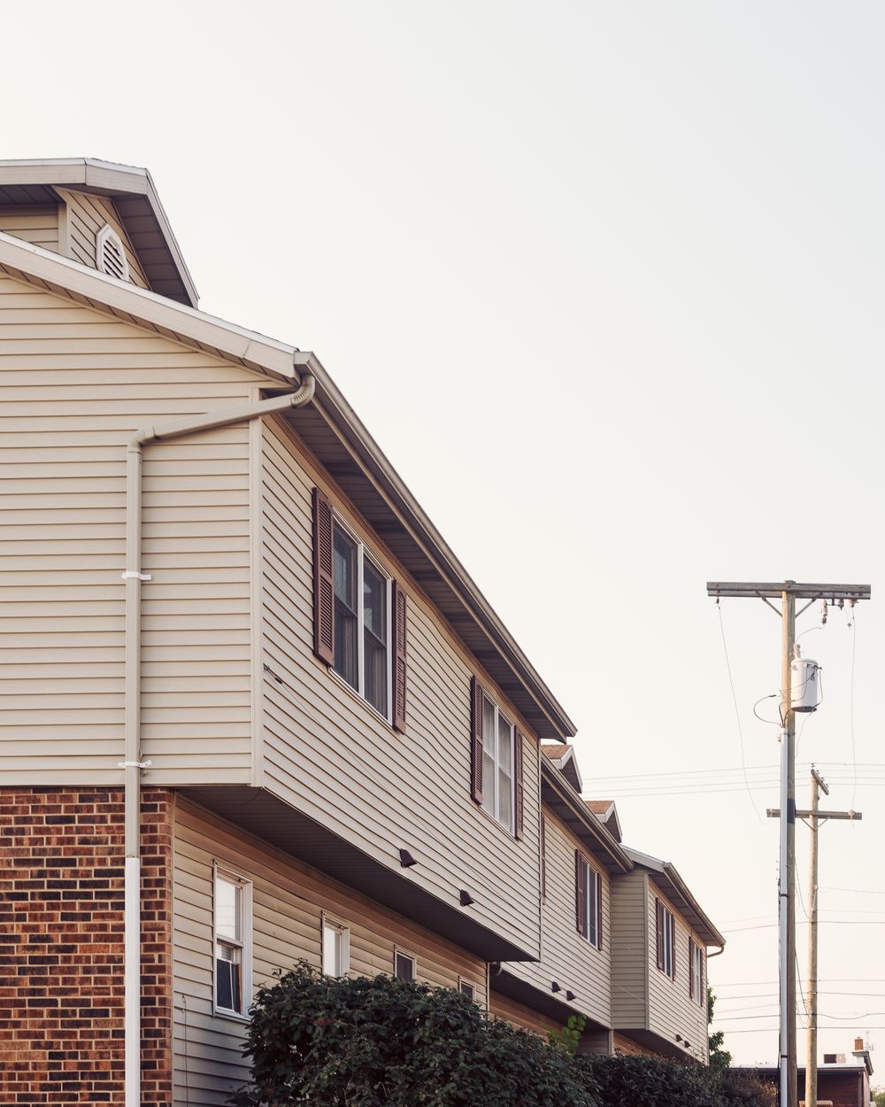 Neighboring residential homes with brick and light-colored siding beside an overhead utility line